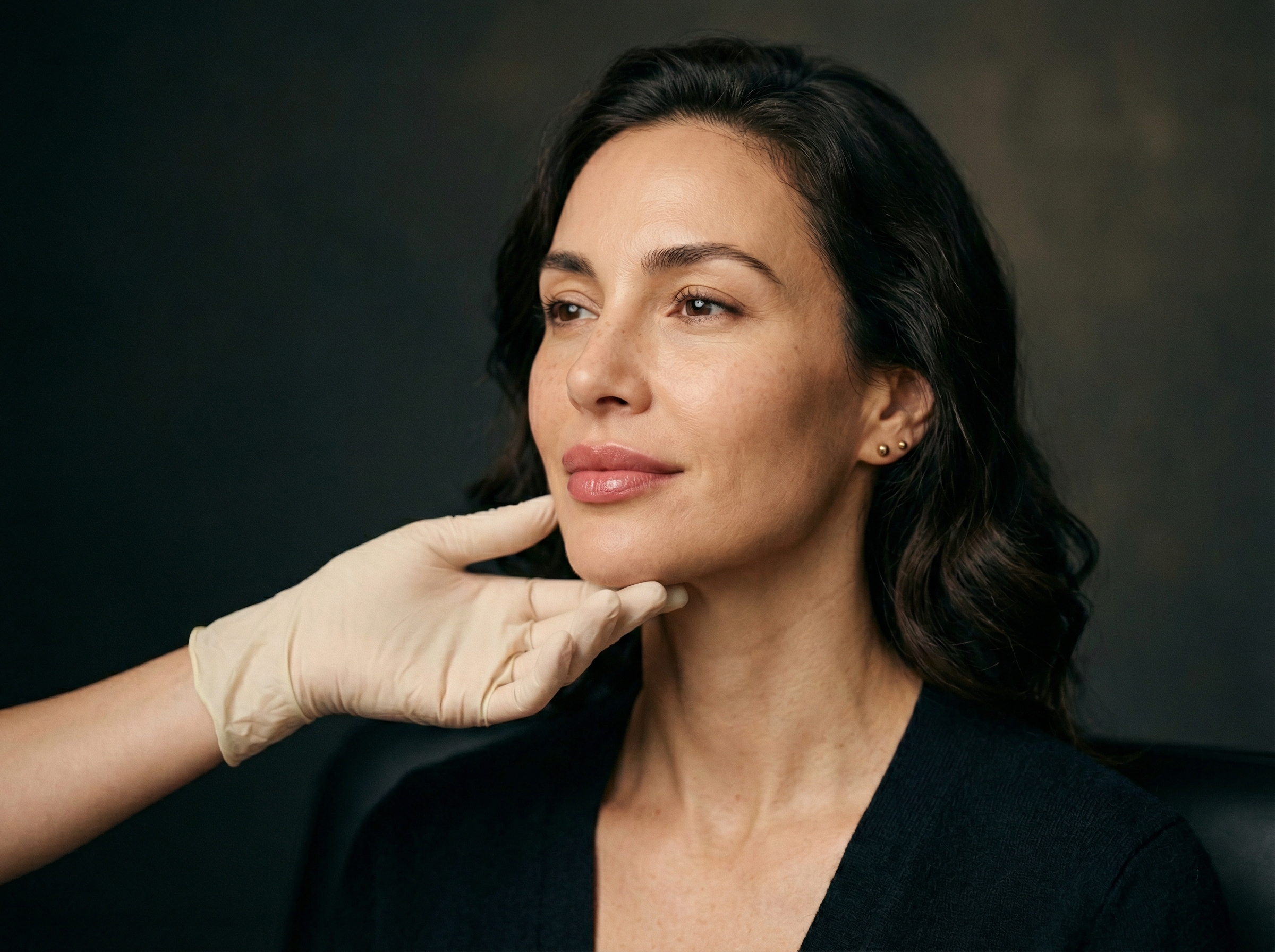 Unisorrir profissional com luva avaliando o contorno facial de uma paciente