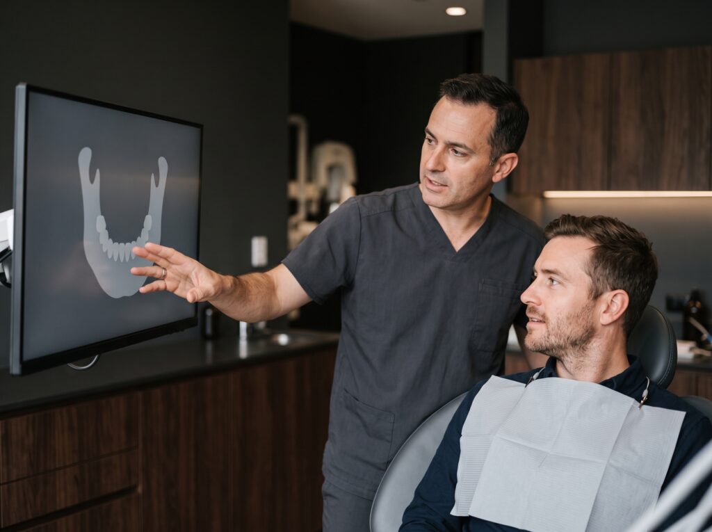 dentista mostrando exame de imagem da arcada dentária a paciente durante avaliação clínica