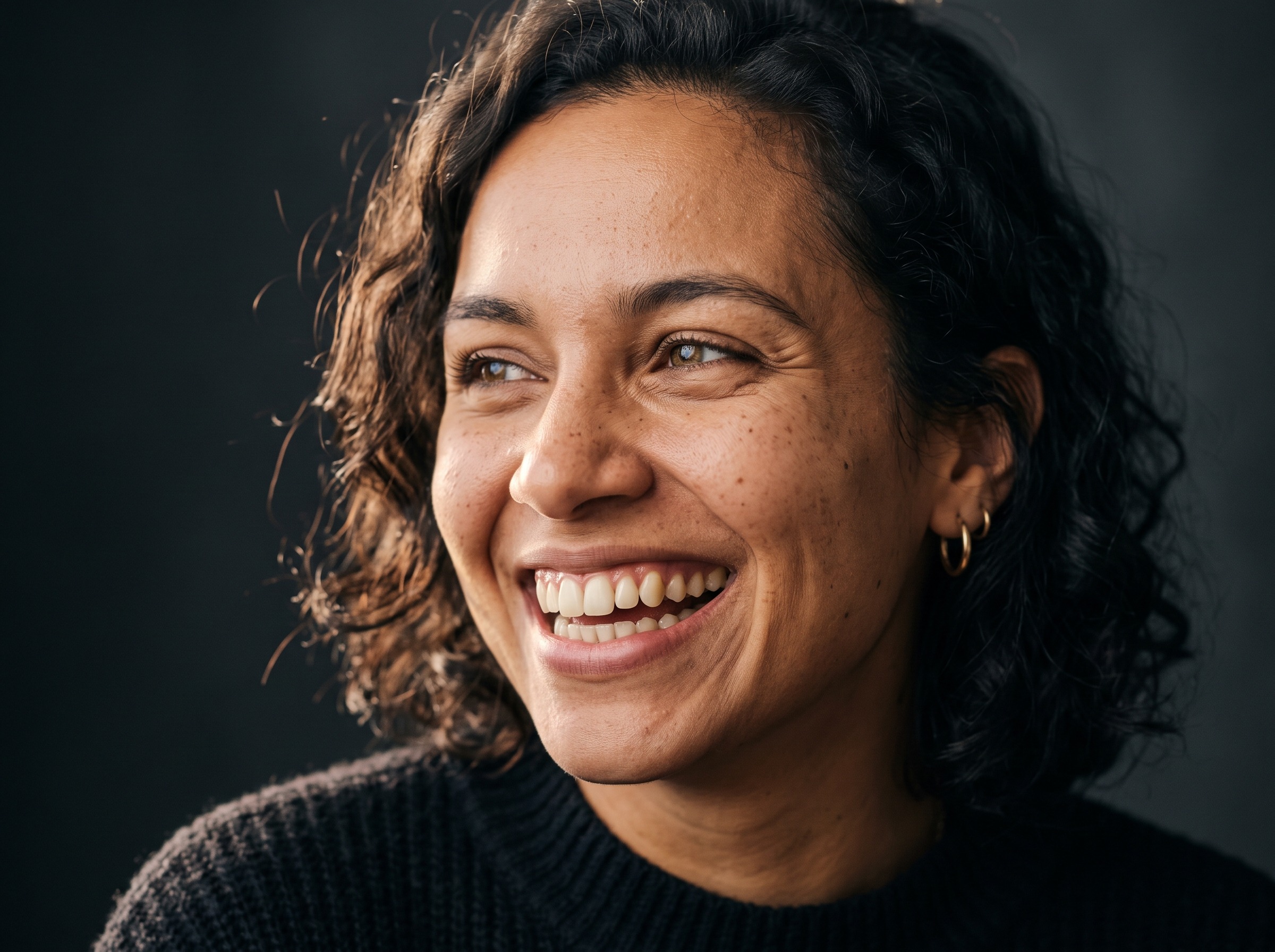 Unisorrir imagem ilustrativa de pessoa sorrindo naturalmente em retrato editorial de luz suave sobre fundo escuro